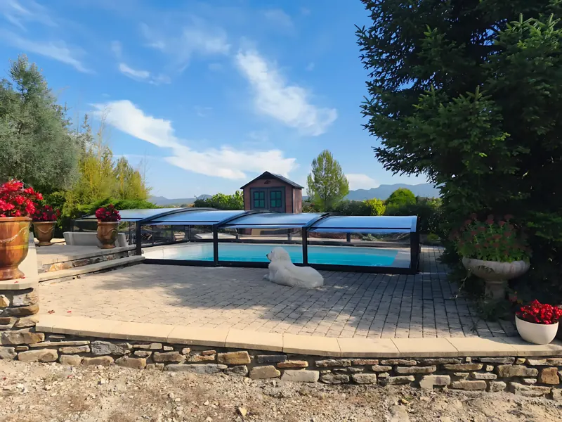 Abri de piscine bas télescopique à structure noire sur un bassin enterré