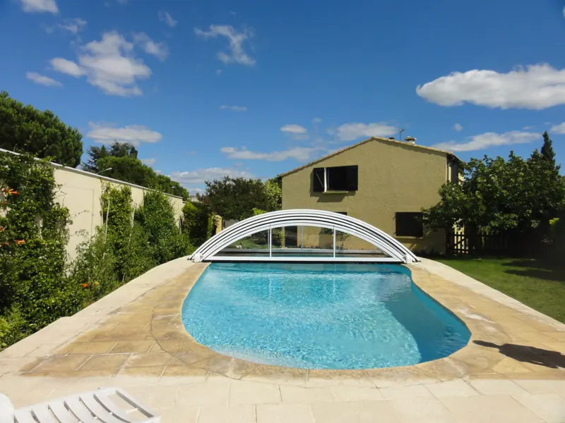 Abri de piscine bas en arc au-dessus d’un bassin bordé d’une plage claire
