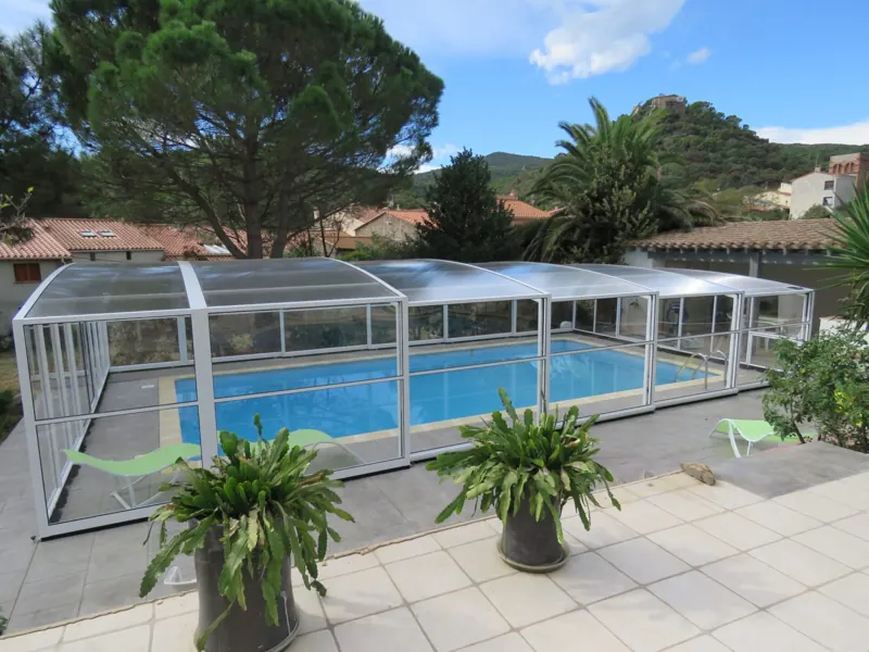 Abri de piscine haut à structure blanche autour d’un bassin
