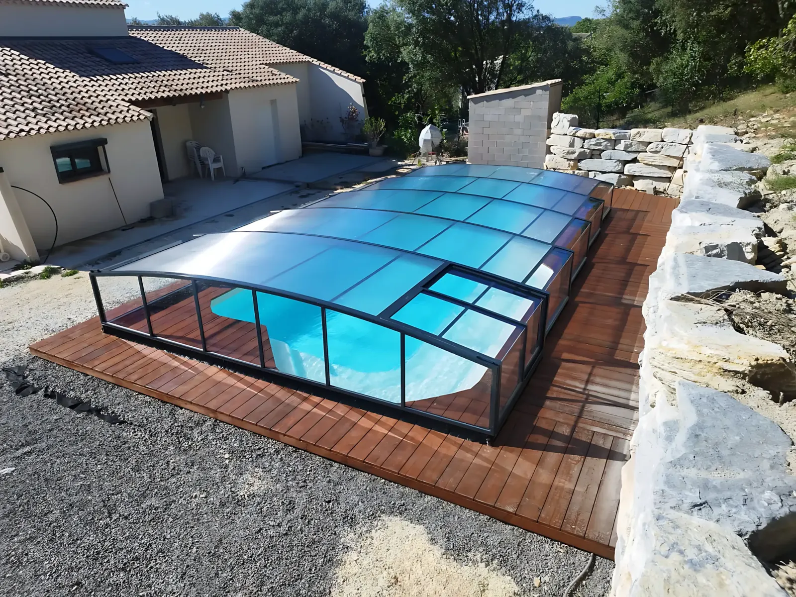Abri de piscine medium télescopique à structure noire, posé sur un bassin au bord d’une terrasse en bois